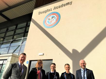 five people stand in foreground with Douglas academy sign behind